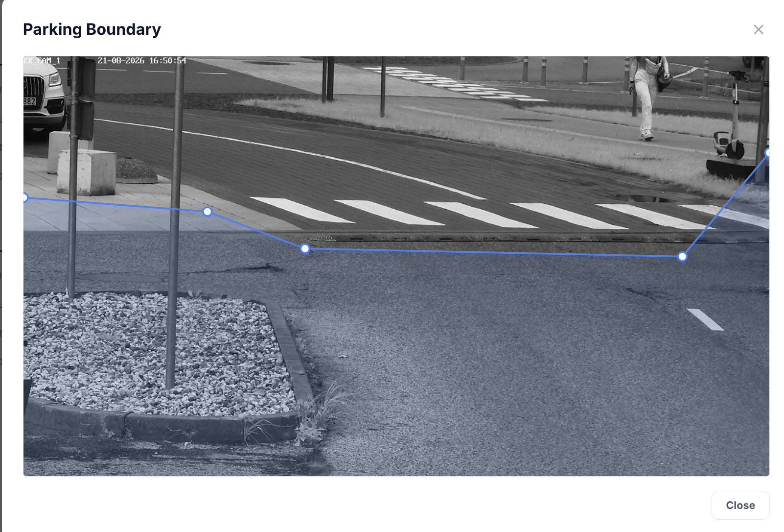 Camera view of a parking entrance with a polygon parking boundary drawn over the asphalt