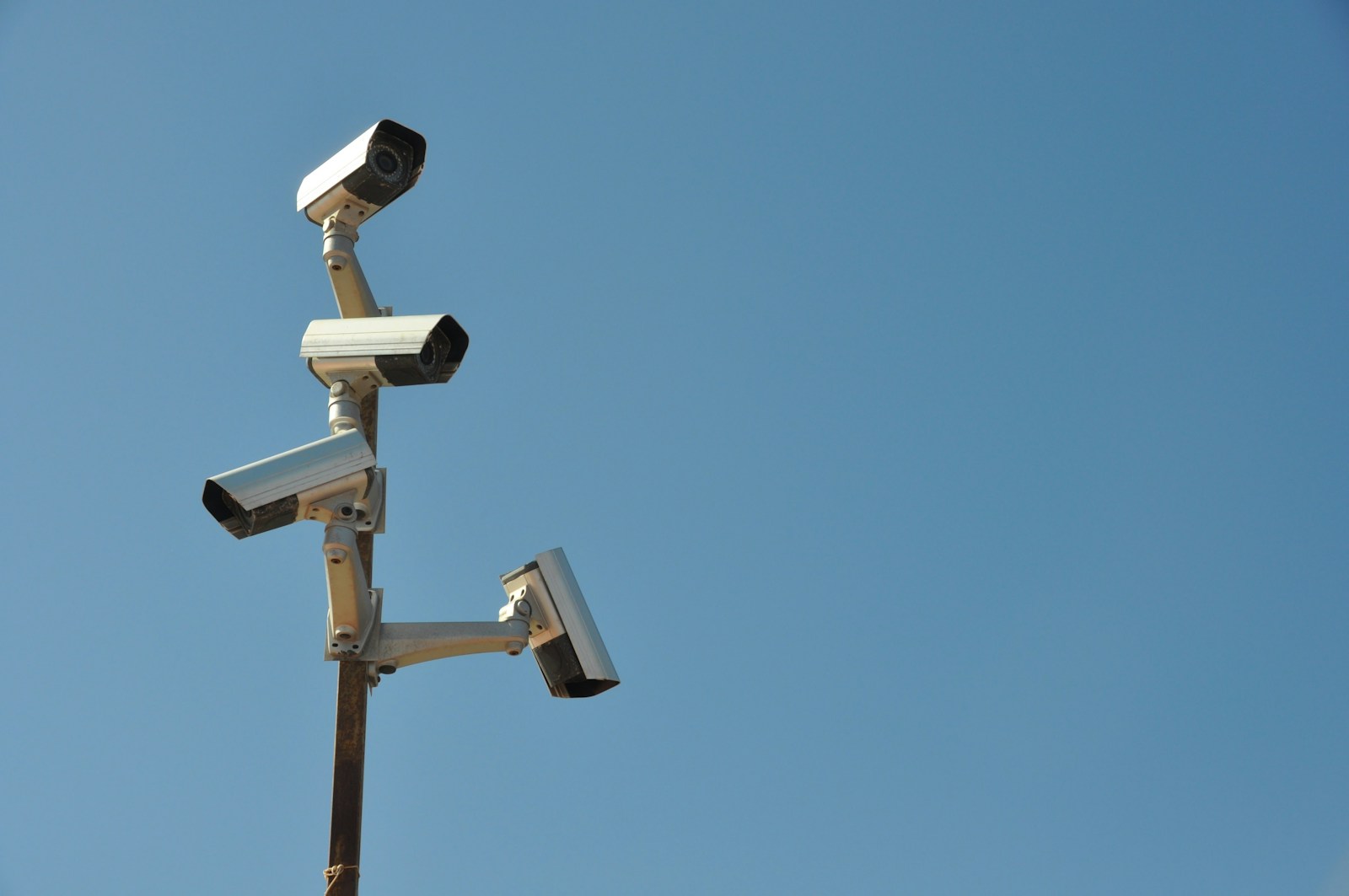 Multiple IP surveillance cameras mounted on a pole against a clear sky