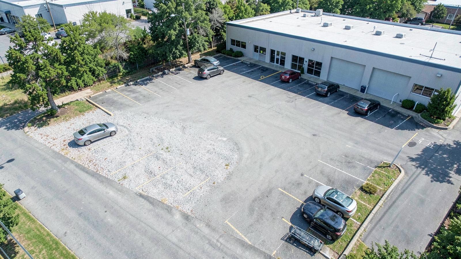 Aerial view of a small parking lot with marked bays beside a commercial building